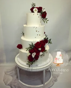 Elegancki tort weselny z białym kremem i delikatnymi kwiatami, przygotowany przez Torcikowo u Pauliny